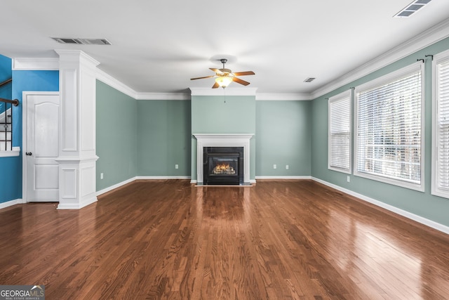 unfurnished living room with a glass covered fireplace, visible vents, crown molding, and ceiling fan