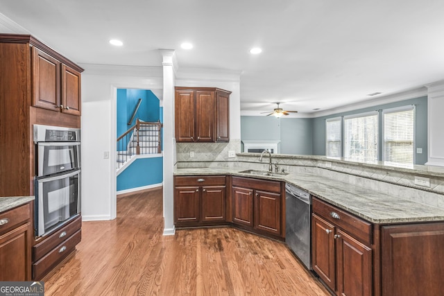 kitchen featuring crown molding, backsplash, appliances with stainless steel finishes, a sink, and wood finished floors