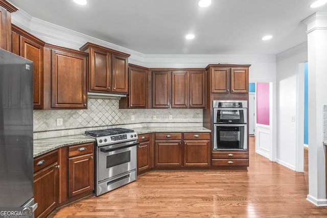 kitchen featuring appliances with stainless steel finishes, light wood-style floors, crown molding, and decorative backsplash