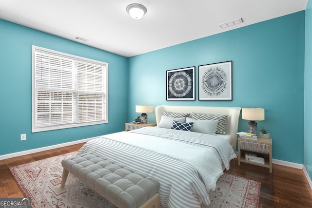 bedroom featuring baseboards, visible vents, and wood finished floors