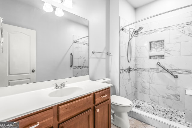 full bathroom with toilet, tiled shower, and vanity