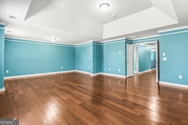 empty room featuring ornamental molding, wood finished floors, visible vents, and baseboards