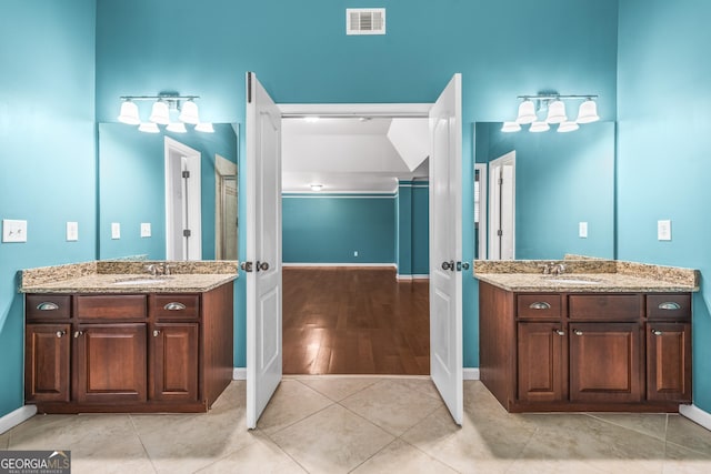 full bath featuring two vanities, visible vents, and a sink