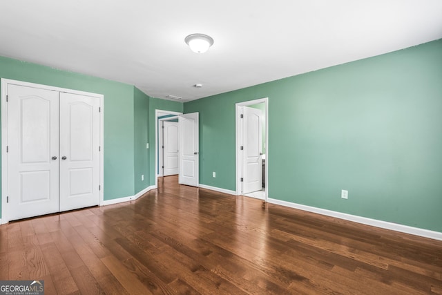 unfurnished bedroom featuring a closet, wood finished floors, and baseboards