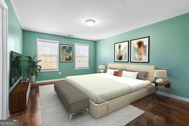 bedroom with visible vents, baseboards, and wood finished floors