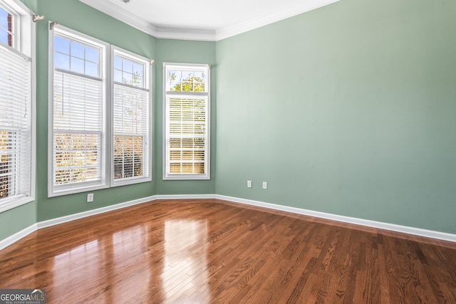 spare room featuring ornamental molding, baseboards, and wood finished floors