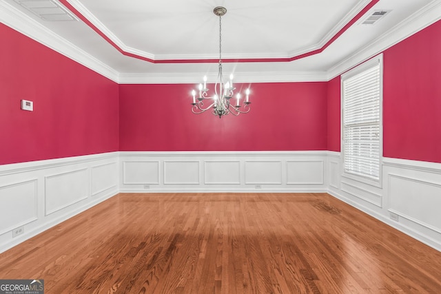 unfurnished dining area featuring wood finished floors, a raised ceiling, visible vents, and a notable chandelier