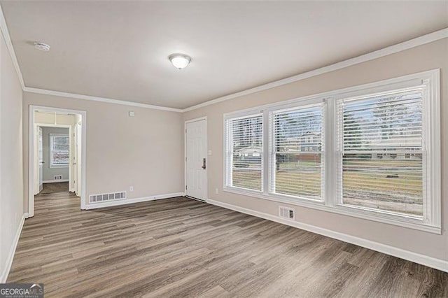 empty room featuring ornamental molding and wood-type flooring