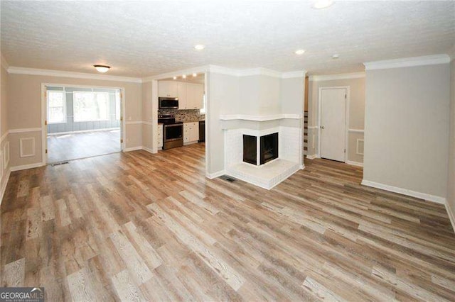 unfurnished living room with a brick fireplace, crown molding, and light hardwood / wood-style floors