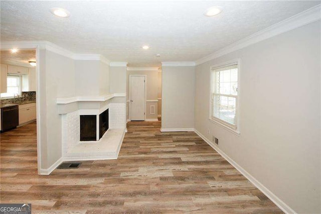 unfurnished living room featuring ornamental molding, a fireplace, and light hardwood / wood-style flooring