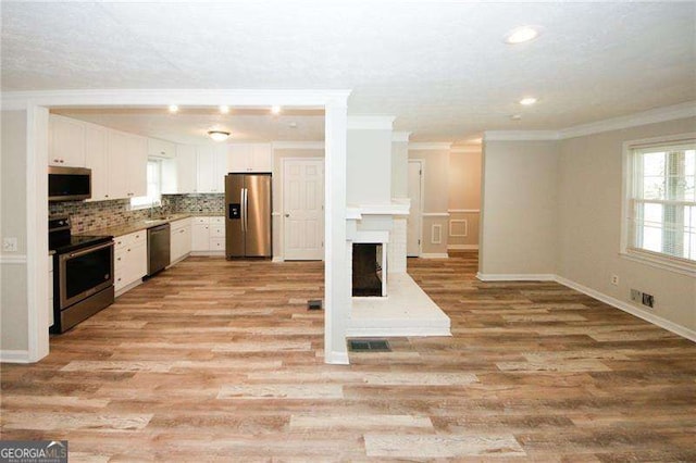 kitchen featuring tasteful backsplash, a healthy amount of sunlight, stainless steel appliances, and white cabinets