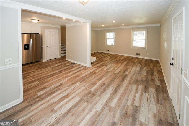 interior space featuring light hardwood / wood-style flooring, crown molding, stainless steel fridge, and a textured ceiling