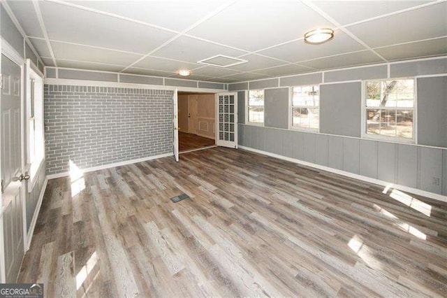 unfurnished room with hardwood / wood-style flooring and brick wall