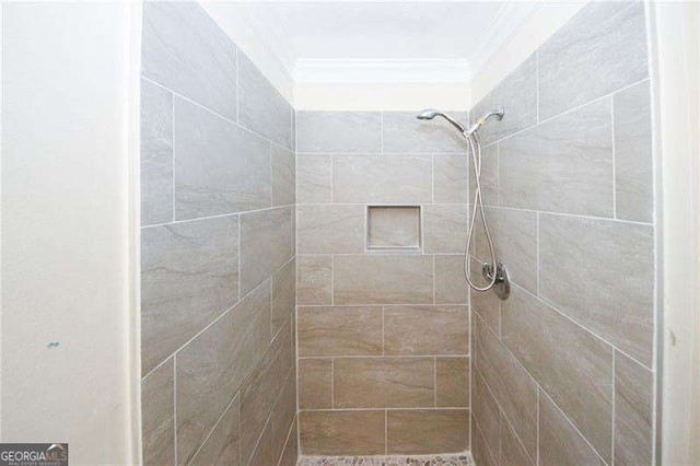 bathroom with ornamental molding and a tile shower