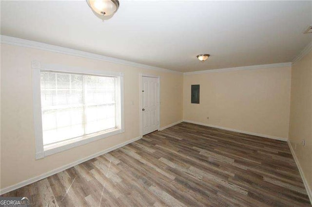 spare room featuring ornamental molding, dark wood-type flooring, and electric panel