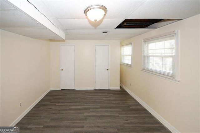 unfurnished room featuring dark hardwood / wood-style flooring and a paneled ceiling