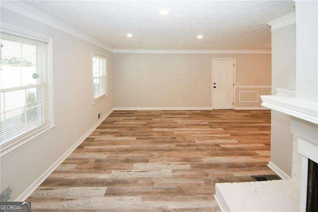 unfurnished living room featuring crown molding, a wealth of natural light, and light wood-type flooring