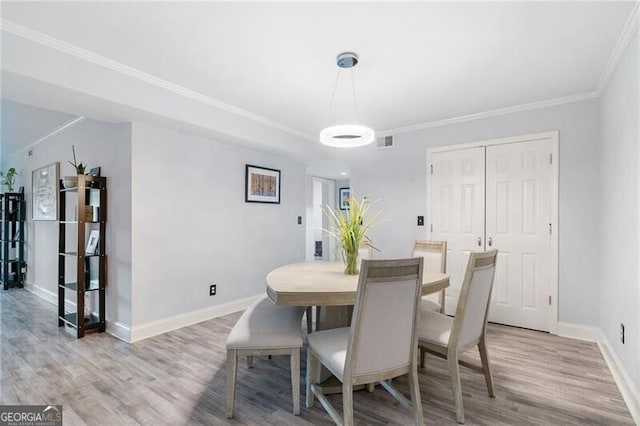 dining area with crown molding and light hardwood / wood-style floors