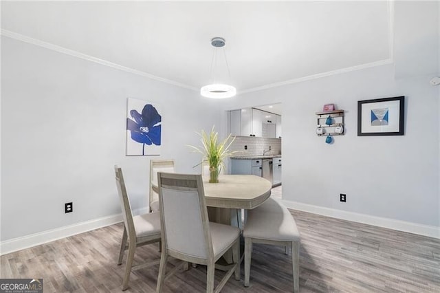 dining area with light hardwood / wood-style flooring and ornamental molding