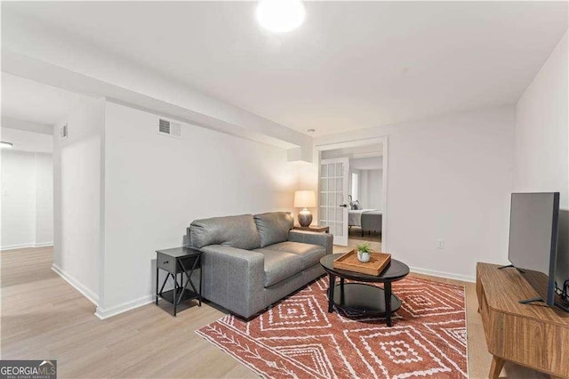living room with french doors and light hardwood / wood-style flooring