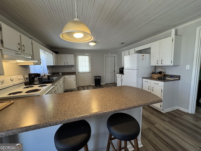 kitchen with a breakfast bar area, white cabinets, white appliances, and kitchen peninsula