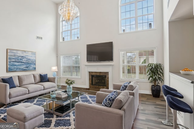 living room featuring a towering ceiling, wood-type flooring, and a chandelier