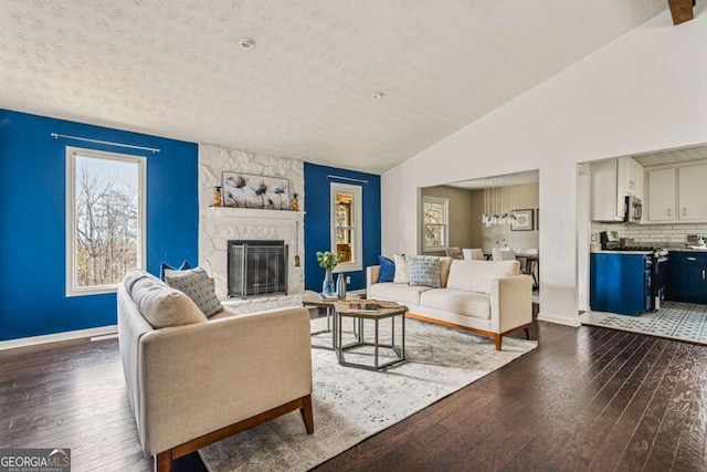 living room featuring hardwood / wood-style flooring, vaulted ceiling, a textured ceiling, and a fireplace