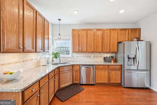 kitchen featuring stainless steel appliances, light stone countertops, light wood-type flooring, and decorative backsplash