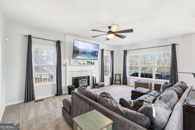 living room featuring ceiling fan, a premium fireplace, and light carpet