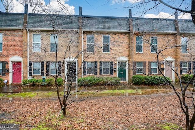 townhome / multi-family property featuring mansard roof, a shingled roof, and brick siding