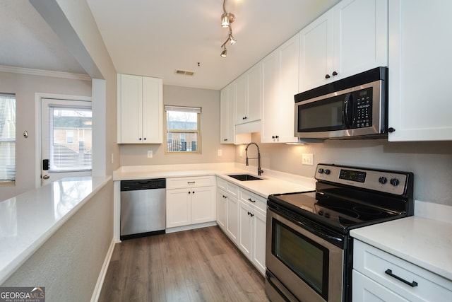 kitchen with a sink, white cabinetry, light countertops, appliances with stainless steel finishes, and light wood finished floors