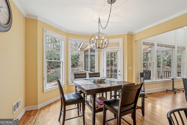 dining space with ornamental molding, a notable chandelier, and light hardwood / wood-style flooring