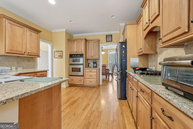 kitchen with stainless steel appliances, ornamental molding, light stone counters, and light hardwood / wood-style flooring