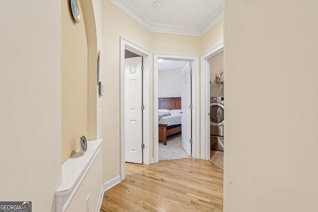 hallway with crown molding, washer / dryer, and light wood-type flooring