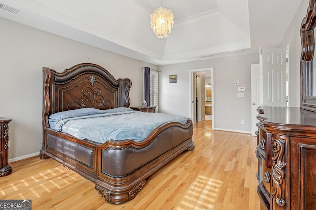 bedroom with an inviting chandelier, a tray ceiling, and hardwood / wood-style floors