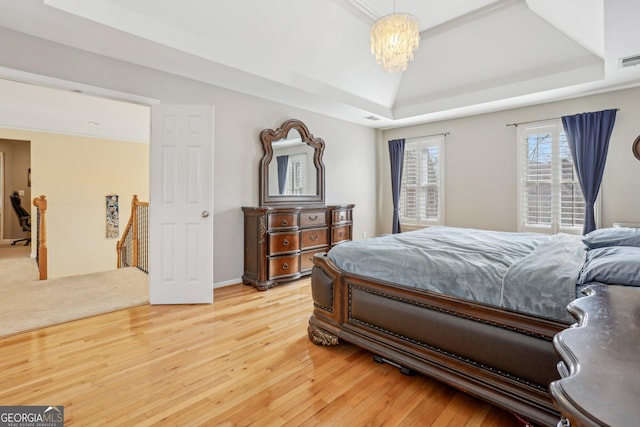 bedroom featuring hardwood / wood-style flooring, a notable chandelier, and a tray ceiling