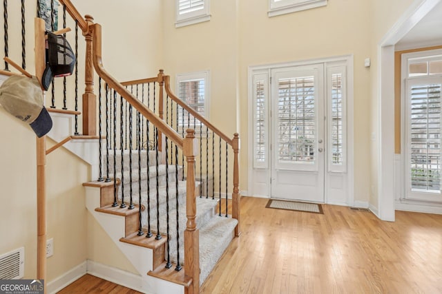 entrance foyer featuring a towering ceiling and light wood-type flooring