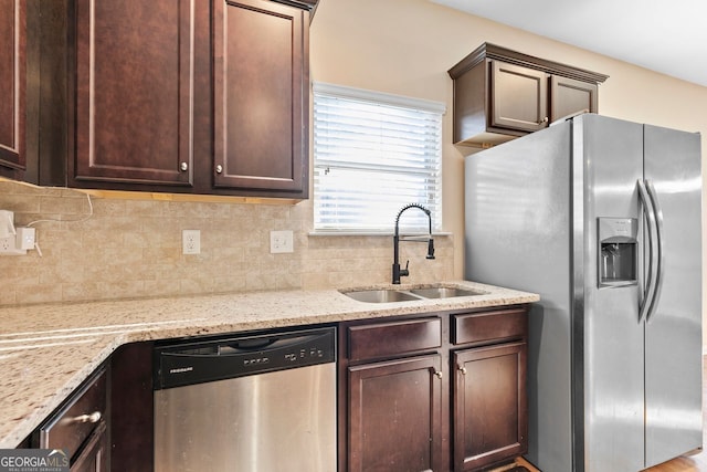 kitchen featuring sink, backsplash, light stone counters, stainless steel appliances, and dark brown cabinetry