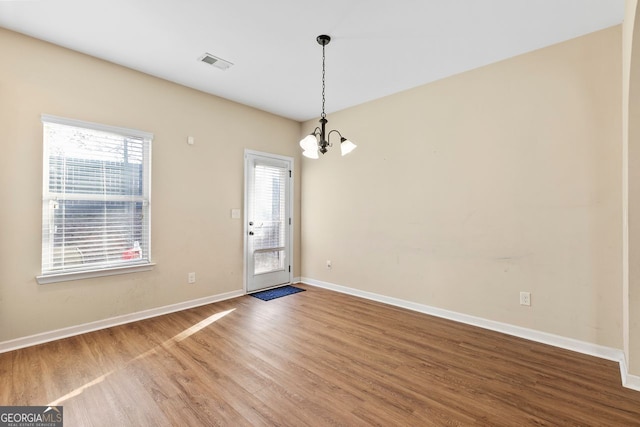 spare room featuring hardwood / wood-style flooring and a notable chandelier