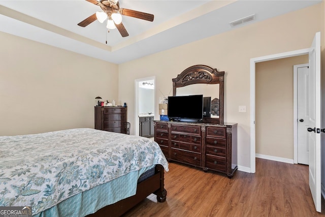 bedroom with a tray ceiling, hardwood / wood-style flooring, and ceiling fan