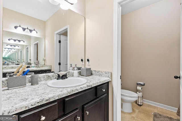bathroom with toilet, vanity, and tile patterned flooring
