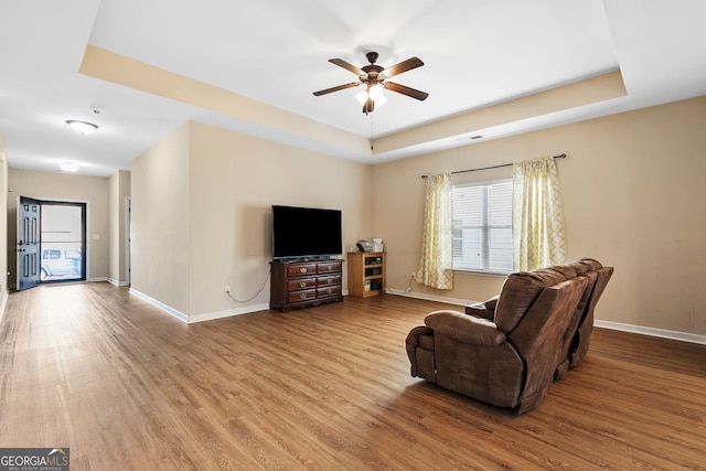 unfurnished living room with ceiling fan, wood-type flooring, and a raised ceiling