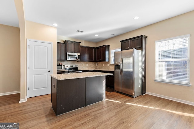 kitchen with light hardwood / wood-style flooring, stainless steel appliances, dark brown cabinetry, and a center island