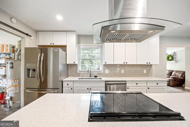 kitchen with appliances with stainless steel finishes, water heater, white cabinetry, sink, and a barn door