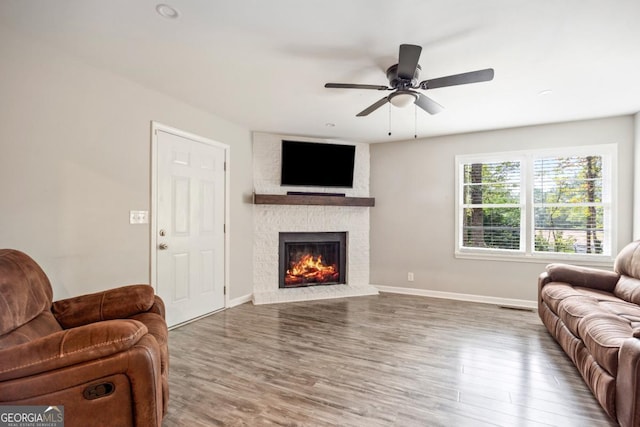 living room with ceiling fan, wood-type flooring, and a fireplace