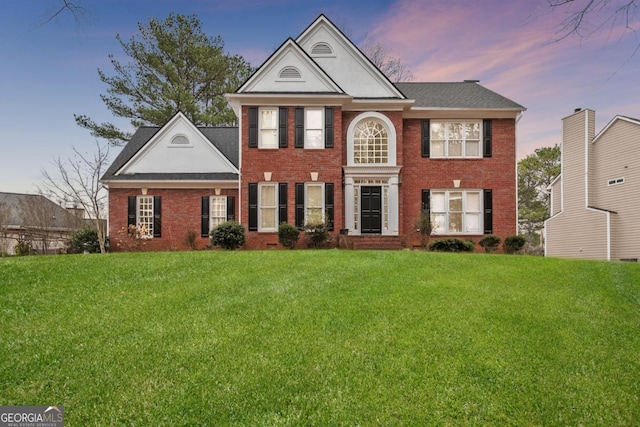 view of front of property featuring a yard and brick siding