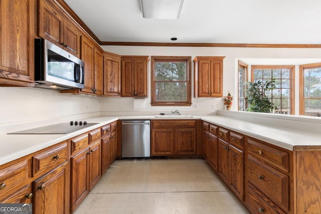 kitchen featuring appliances with stainless steel finishes, brown cabinets, ornamental molding, light countertops, and a sink