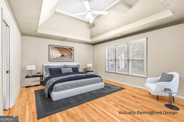 bedroom featuring a tray ceiling, ceiling fan, baseboards, and wood finished floors