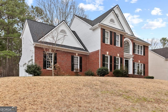 view of front of house featuring a shingled roof, a front yard, and brick siding