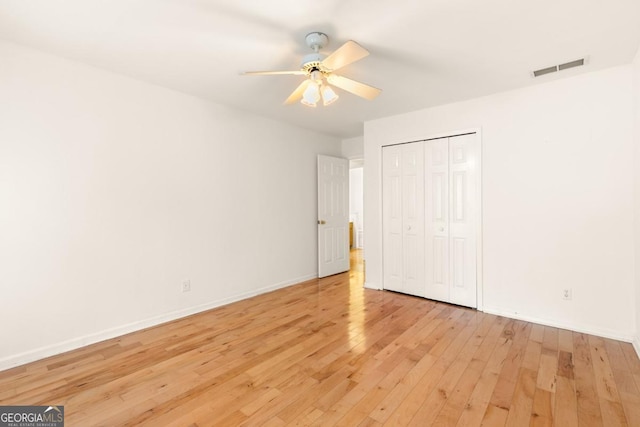 unfurnished bedroom with light wood finished floors, baseboards, visible vents, a ceiling fan, and a closet